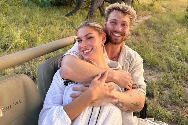 Sam hugs girlfriend Zara as they beam into the camera, with the couple wearing white