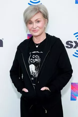 A picture of Sharon with blonde hair, wearing a black outfit