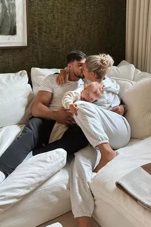 Molly-Mae Hague and Tommy Fury and daughter Bambi sitting on the couch in their living room