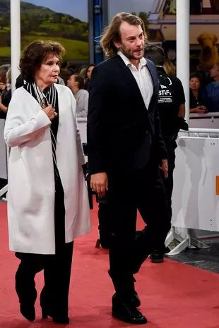 Angus in a suit walking with a older looking woman