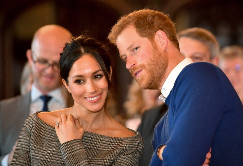 Prince Harry whispers to Meghan Markle as they watch a dance performance by Jukebox Collective in the banqueting hall during a visit to Cardiff Castle on January 18, 2018 in Cardiff, Wales.