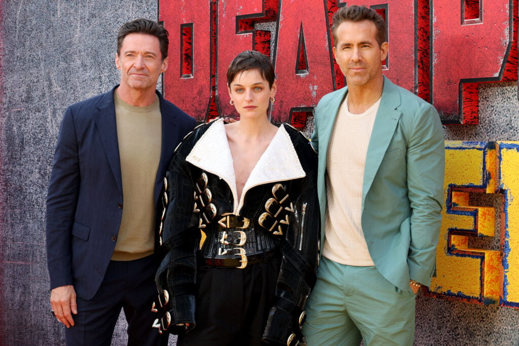 Emma Corrin stands between Hugh Jackman and Ryan Reynolds while promoting Deadpool & Wolverine.