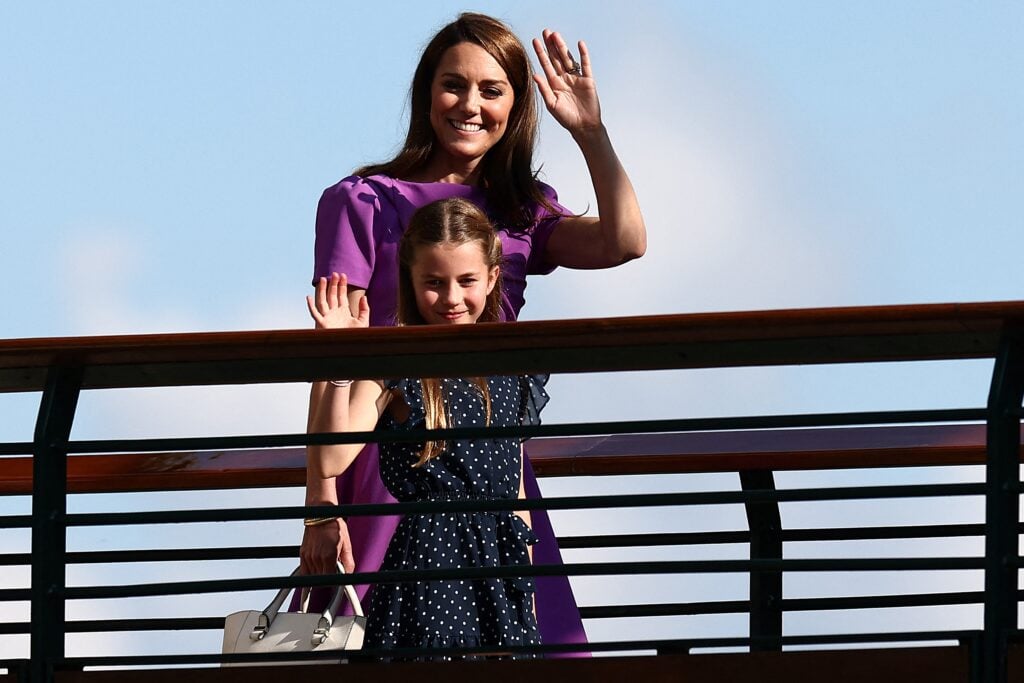 Britain's Catherine, Princess of Wales and Britain's Princess Charlotte of Wales (front) wave as they cross the bridge as they leave Centre Court after attending the men's singles final tennis match on the fourteenth day of the 2024 Wimbledon Championships. 