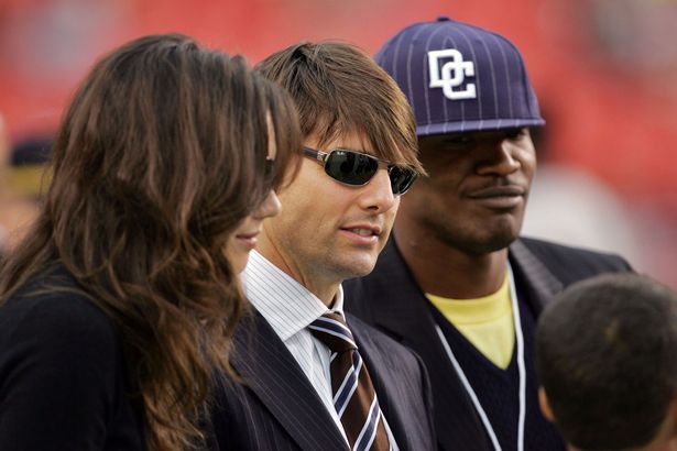 Tom Cruise, Katie Holmes and Jamie Foxx stand on the field before a game between the Minnesota Vikings and the Washington Redskins during the first Monday Night Football game of the season on September 11, 2006